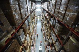 High-bay warehouse with palletised goods and inventory stored on industrial shelving racks.